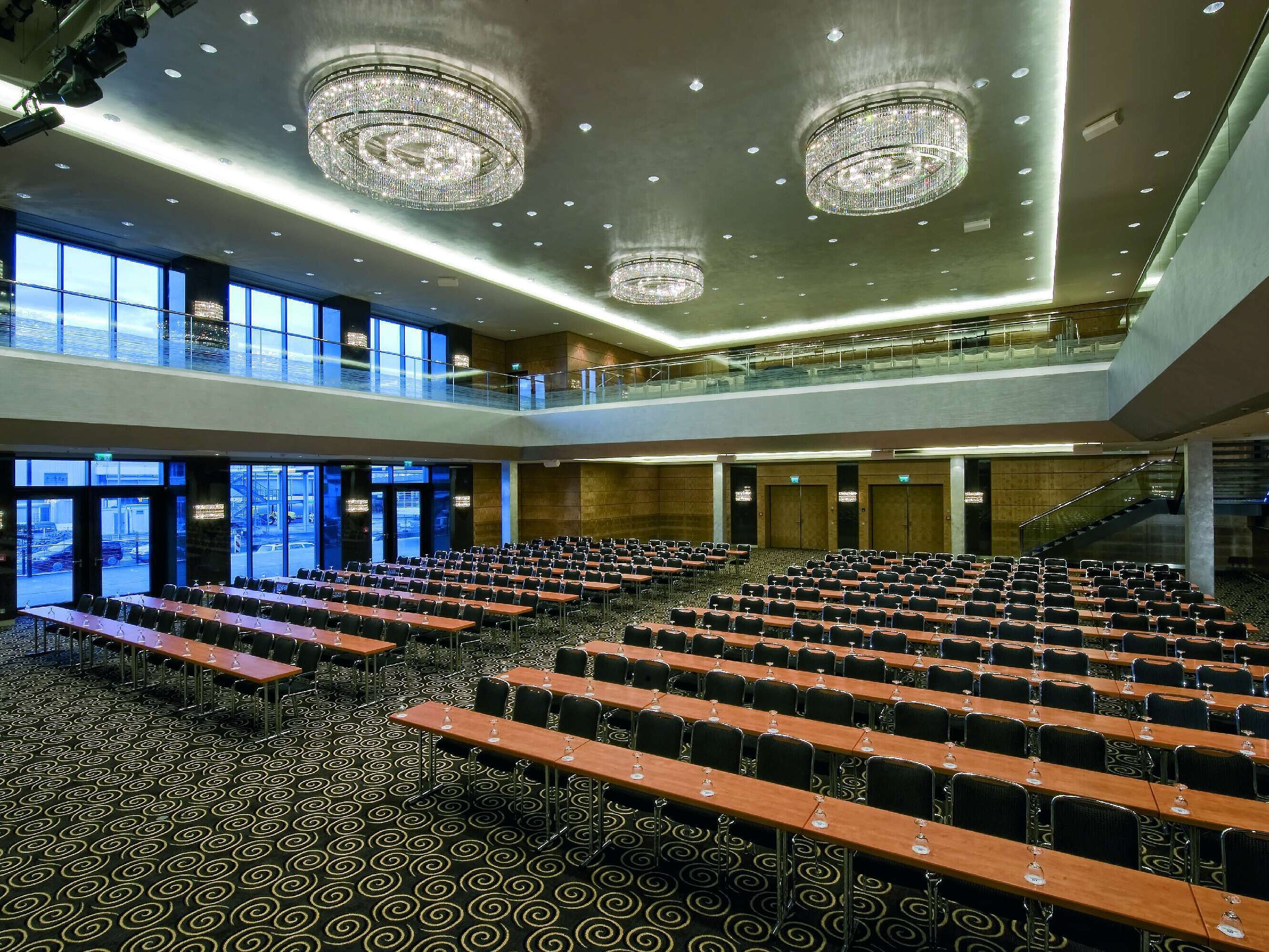 Moderner Saal im Maritim Hotel Düsseldorf mit Reihenbestuhlung, großen Fenstern und beeindruckenden Kronleuchtern.
