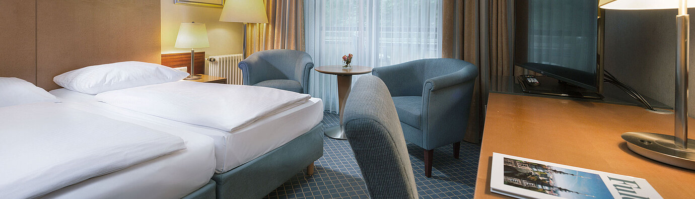 Comfort Doppelzimmer im Maritim Hotel Fulda mit modernen Möbeln, Schreibtisch und gemütlicher Sitzecke.