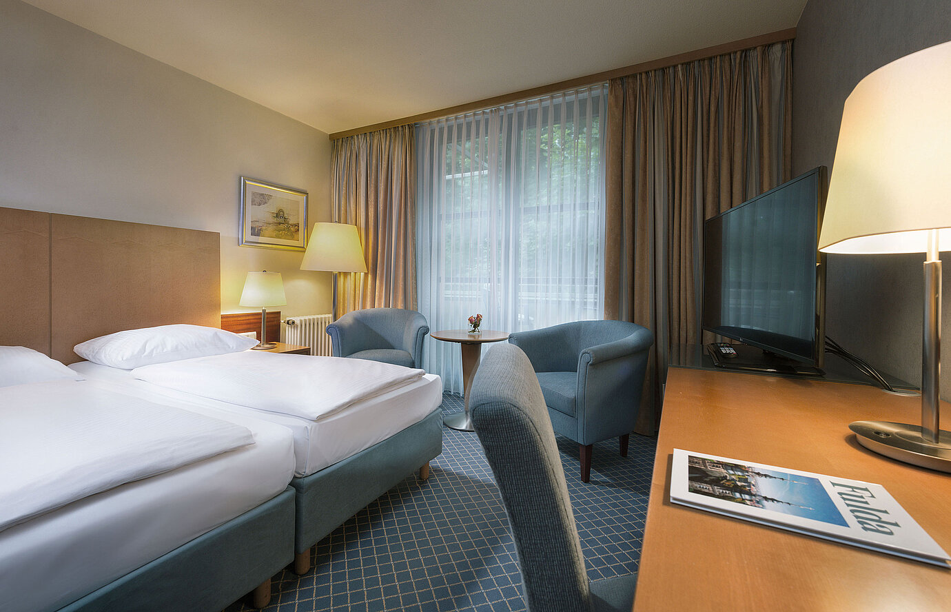 Comfort Doppelzimmer im Maritim Hotel Fulda mit modernen Möbeln, Schreibtisch und gemütlicher Sitzecke.