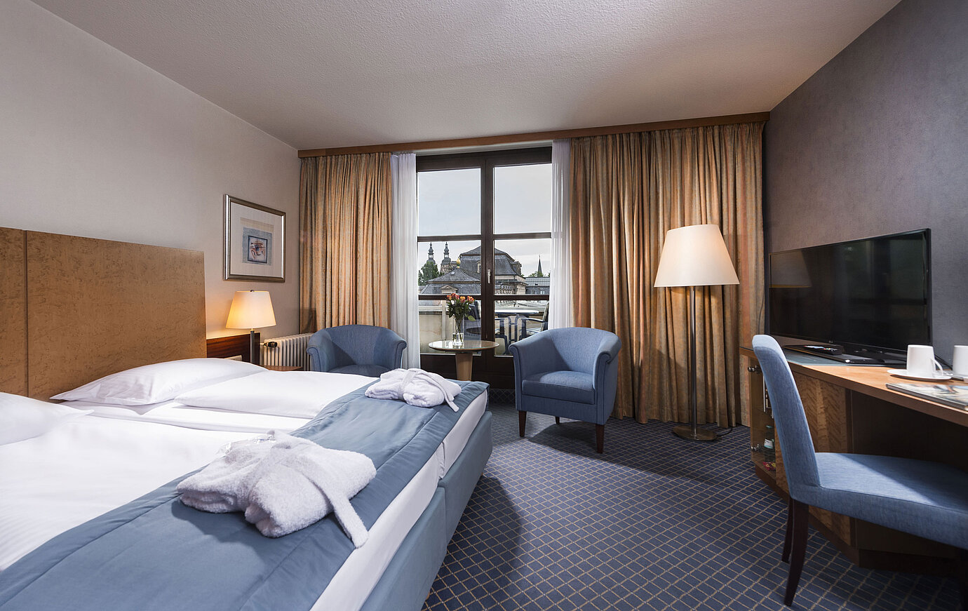 Elegantes Superior Zimmer im Maritim Hotel Fulda mit Doppelbett, Sitzbereich und Balkon mit Blick auf die Stadt.