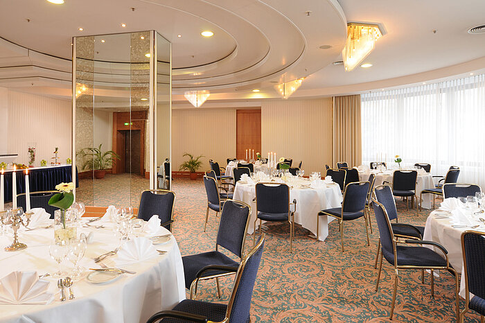 Salon Dresden im Maritim Hotel Magdeburg mit eleganten, weiß gedeckten Tischen, Kerzenleuchtern und stilvoller Beleuchtung für festliche Anlässe.