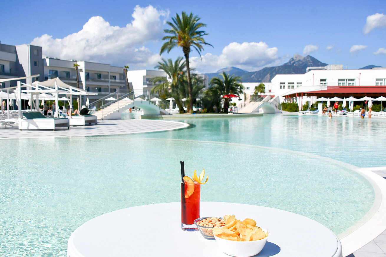 Snacks und ein Cocktail am Lagunenpool des Maritim Resort Calabria. Perfekte Auszeit mit Blick auf die Berge.
