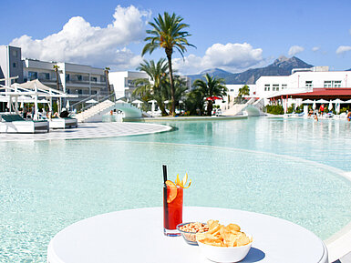 Snacks und ein Cocktail am Lagunenpool des Maritim Resort Calabria. Perfekte Auszeit mit Blick auf die Berge.