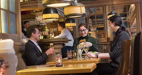 Gäste genießen eine Mahlzeit und Getränke in der Bier- und Weinstube "Kölsche Stuff" in gemütlicher Atmosphäre.