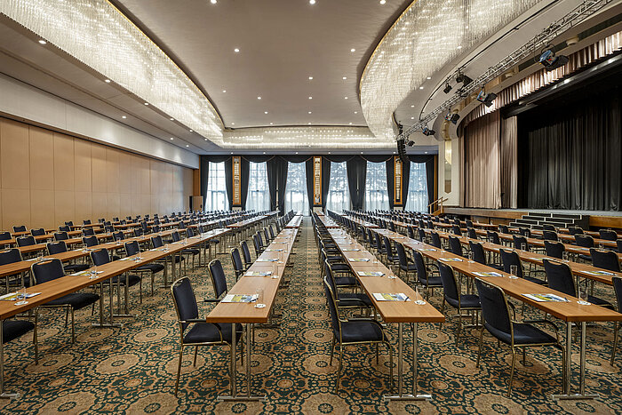 Prächtiger Saal Maritim im Maritim Hotel Magdeburg mit Bühne, Reihenbestuhlung und luxuriösem Kronleuchter.