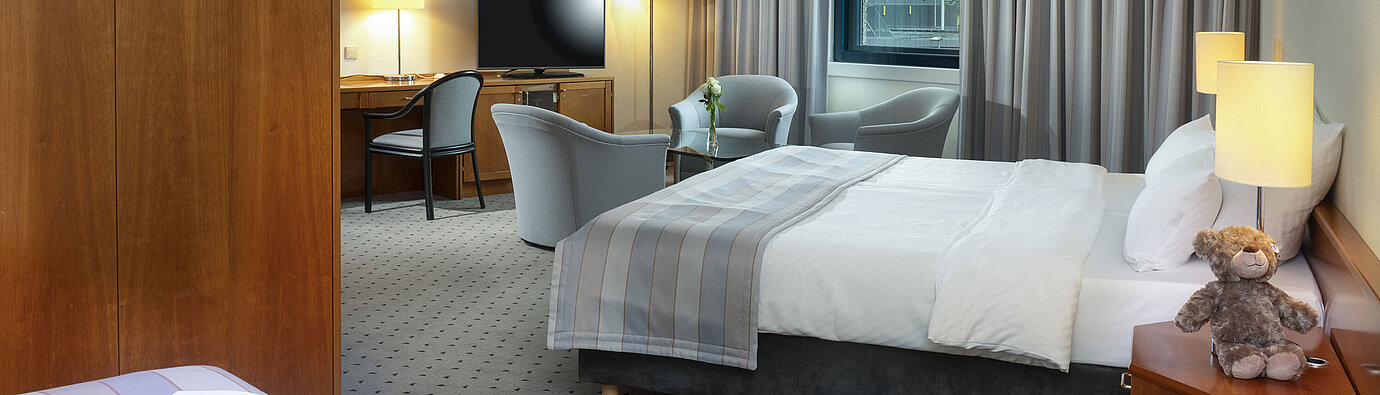 Großzügiges Familienzimmer mit Doppelbett, Sitzecke und Blick auf den Flughafen im Maritim Hotel Hannover.