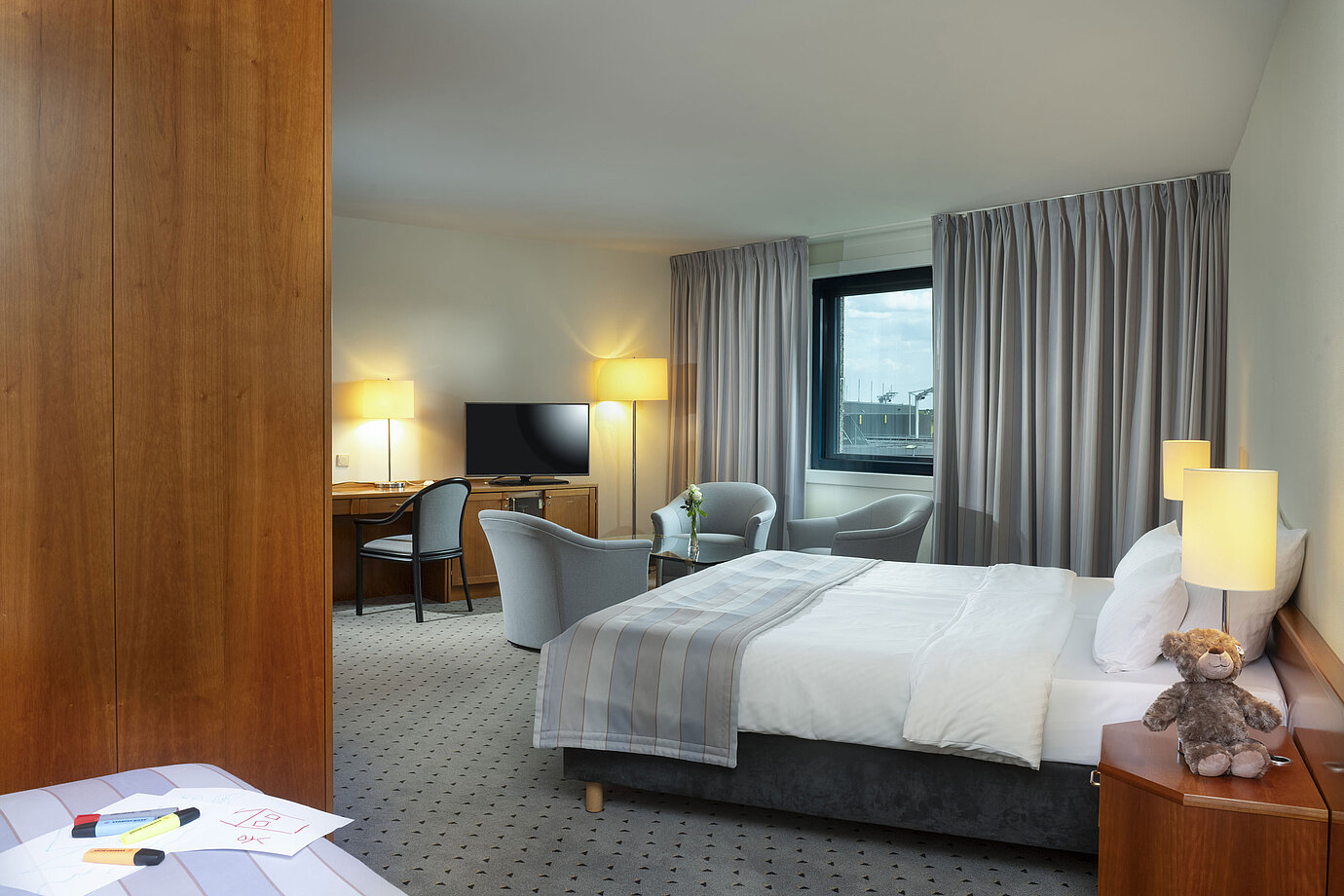 Großzügiges Familienzimmer mit Doppelbett, Sitzecke und Blick auf den Flughafen im Maritim Hotel Hannover.