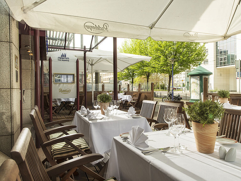 Terrasse Die Terrasse des Maritim Hotels mit gedeckten Tischen, einer entspannenden Atmosphäre und viel natürlichem Licht im Außenbereich.