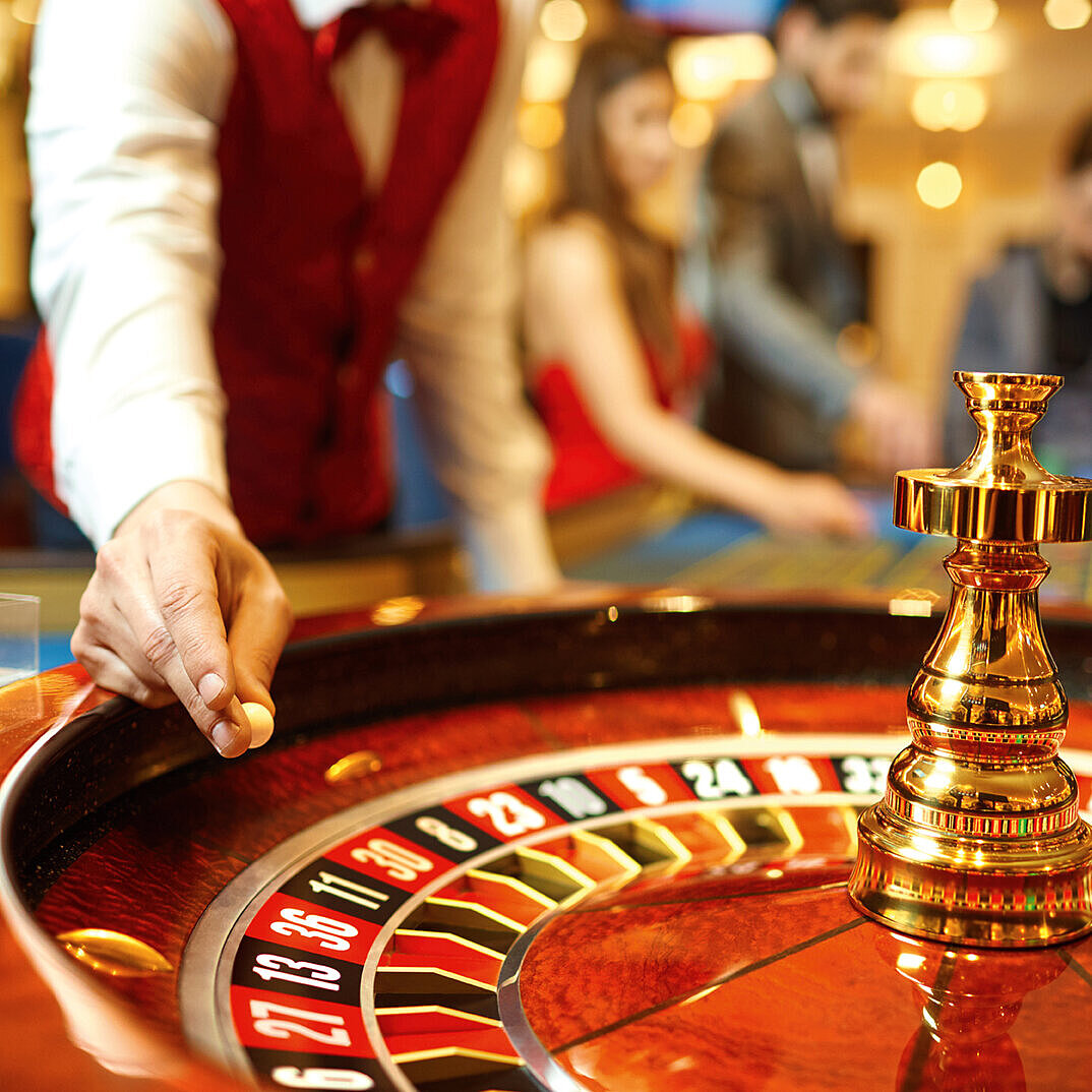 © Studio Romantic - AdobeStock.com Croupier dreht das Roulette im Casino, während Gäste gespannt auf den Spielverlauf warten.