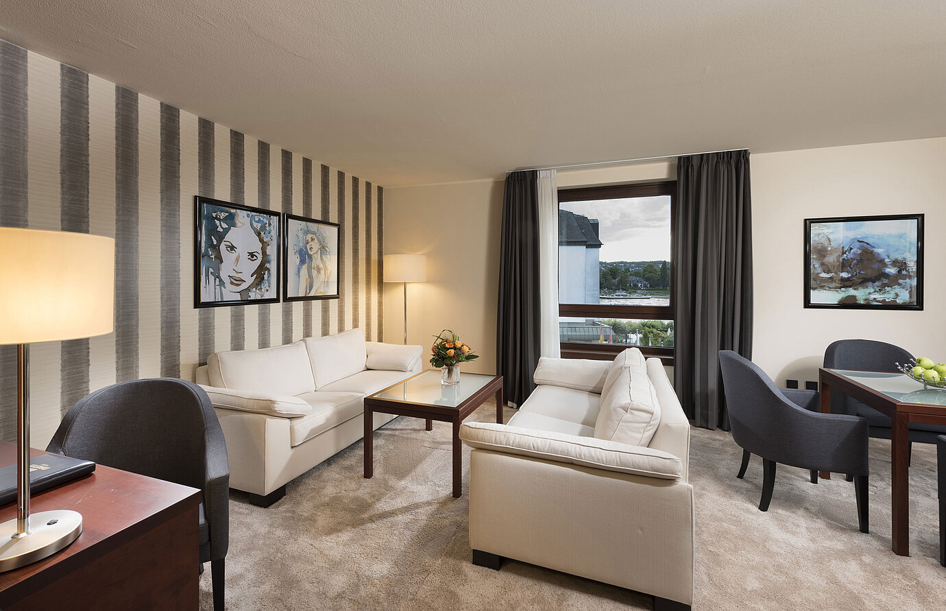 Großzügige Suite mit stilvollen Sofas, Esstisch und Panoramablick auf den Rhein im Maritim Hotel Königswinter.