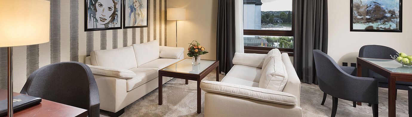 Großzügige Suite mit stilvollen Sofas, Esstisch und Panoramablick auf den Rhein im Maritim Hotel Königswinter.