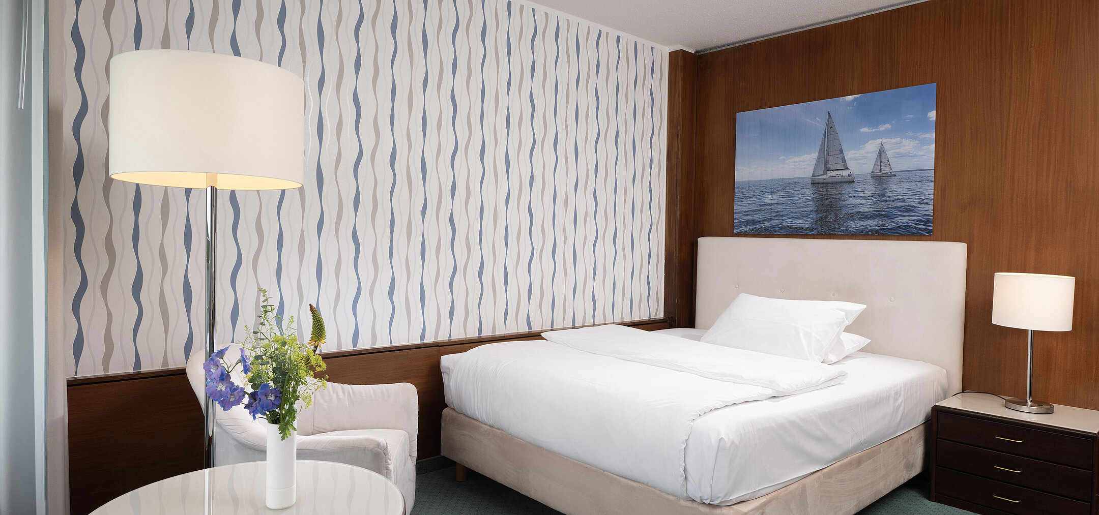 Modernes Zimmer im Maritim Seehotel Timmendorfer Strand mit Segelboot-Motiv und Sitzecke