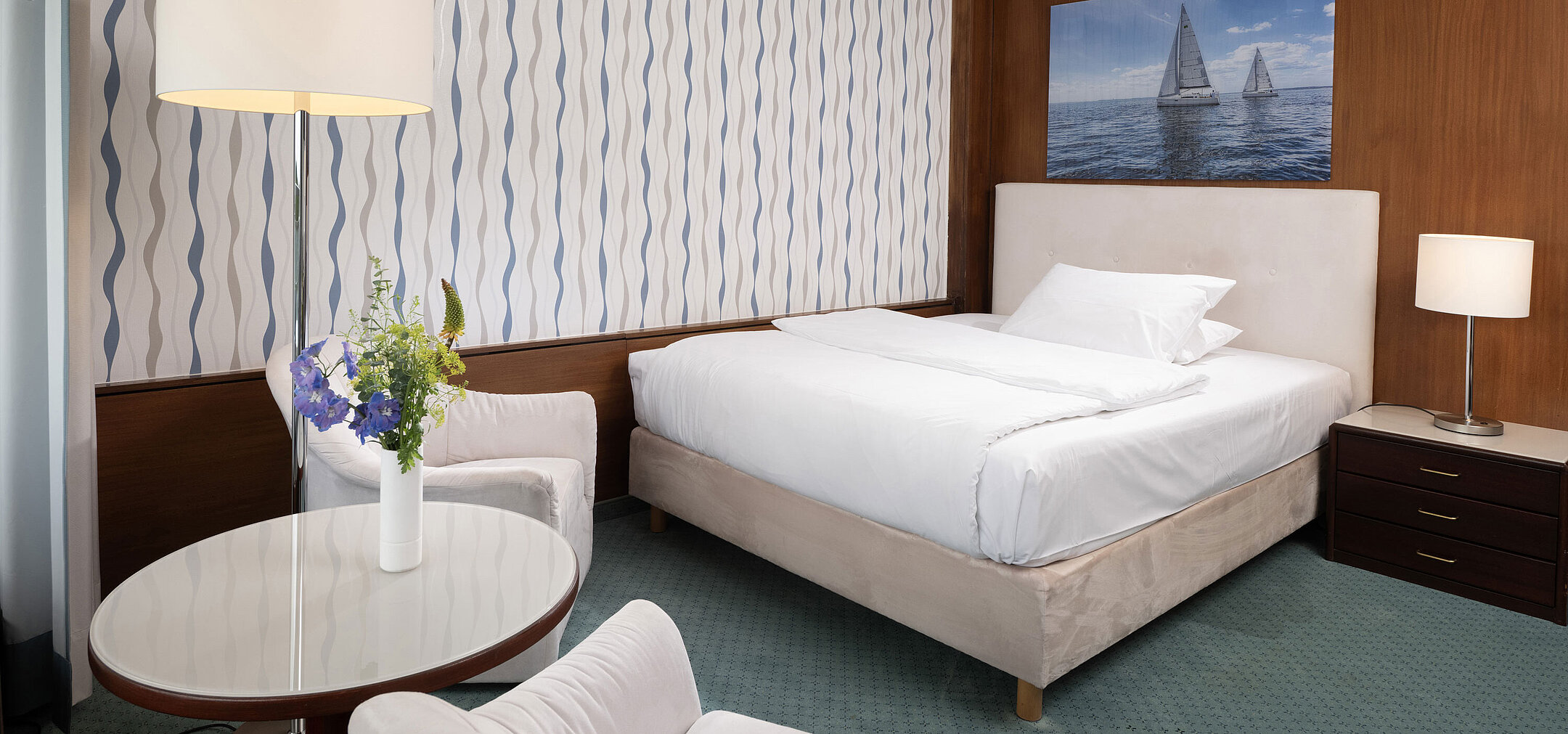 Modernes Zimmer im Maritim Seehotel Timmendorfer Strand mit Segelboot-Motiv und Sitzecke
