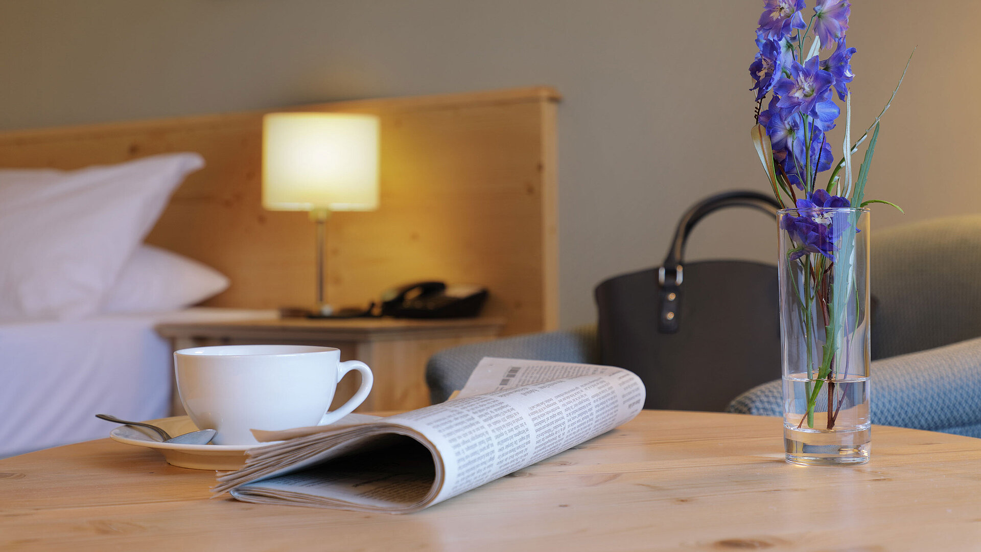 Tasse Kaffee, Zeitung und Blume auf Tisch im Zimmer des Maritim Hotel Titisee