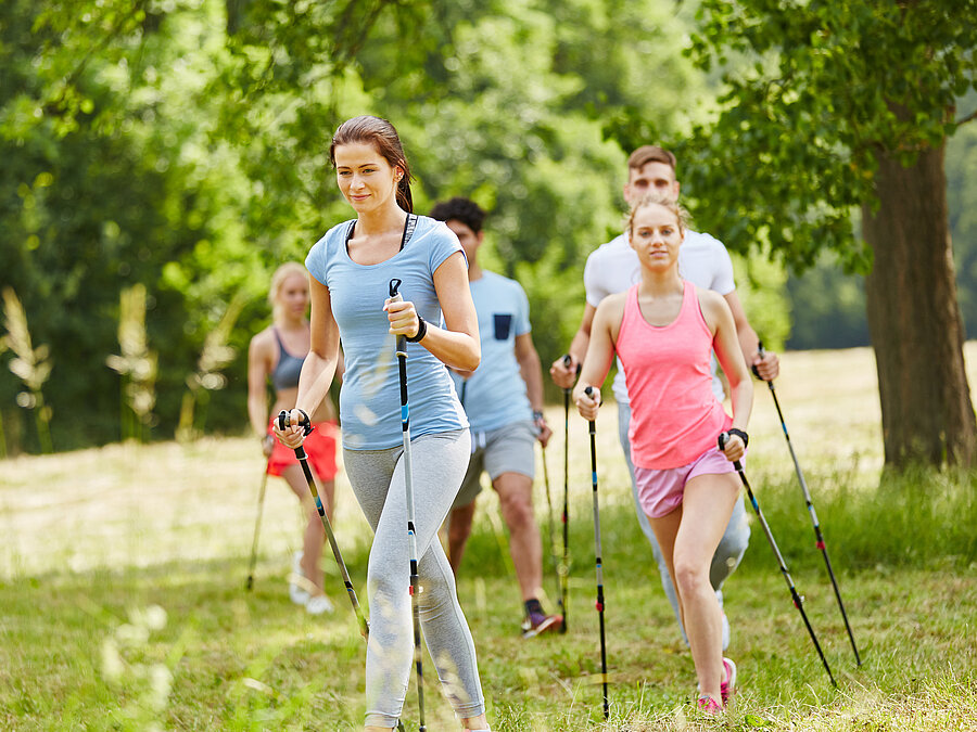 Kolleg:innen beim Spaziergang im Grünen mit Wanderstöcken, gemeinsam aktiv in der Natur.