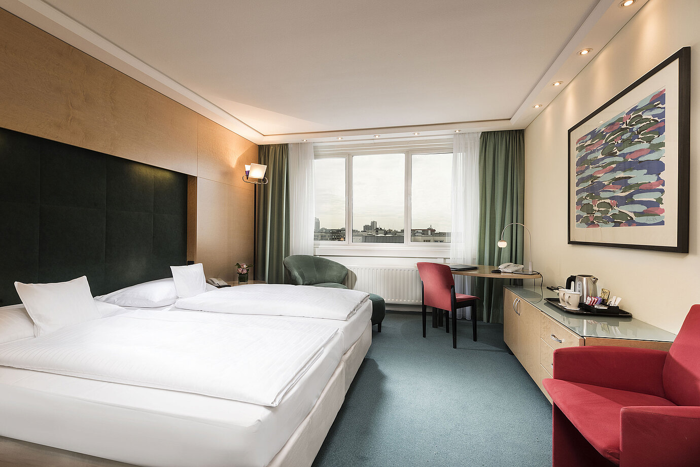 Comfort Zimmer im Maritim proArte Hotel Berlin mit Doppelbett, Schreibtisch, Sessel und Ausblick auf die Stadt.