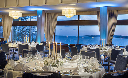Saal Maritim im Maritim Hotel Kiel, festlich gedeckte Tische mit Kerzenlicht, großen Fenstern und Meerblick bei Abenddämmerung