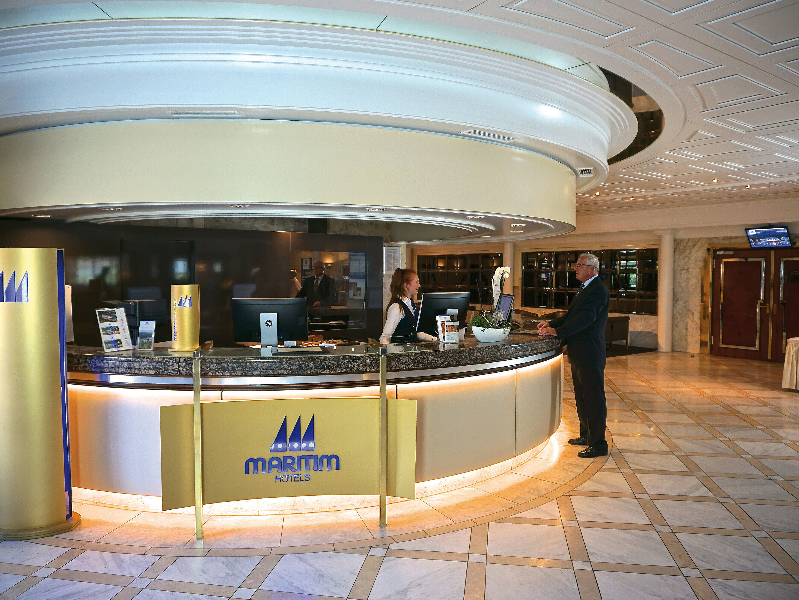 Freundlicher Empfang an der Rezeption des Maritim Hotel Königswinter mit stilvollem Interieur.