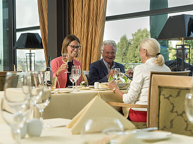 Fröhliche Gäste genießen ein Glas Wein und ein Essen im Restaurant des Maritim Hotel Dresden.