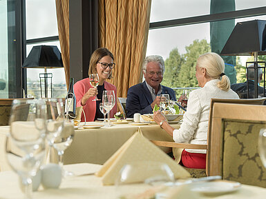 Fröhliche Gäste genießen ein Glas Wein und ein Essen im Restaurant des Maritim Hotel Dresden.
