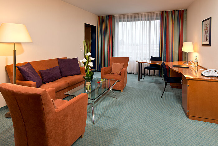Geräumige Junior Suite im Maritim Hotel Frankfurt mit komfortabler Sitzecke, Schreibtisch und warmem Lichtdesign.
