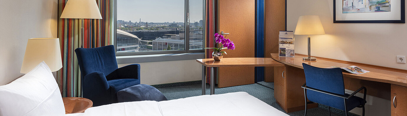 Comfort Familienzimmer Comfort Familienzimmer im Maritim Hotel Frankfurt mit Doppelbett, Schreibtisch, bunten Vorhängen und Blick auf die Stadt.