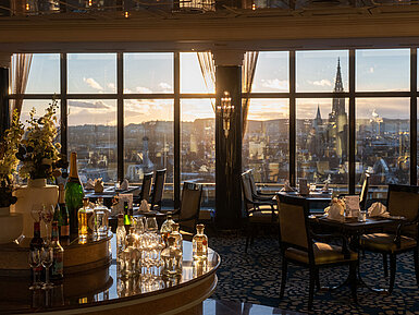 Restaurant im Maritim Hotel Ulm mit Gläsern am Rondell, großen Fenstern und Blick über Ulm bei Sonnenuntergang
