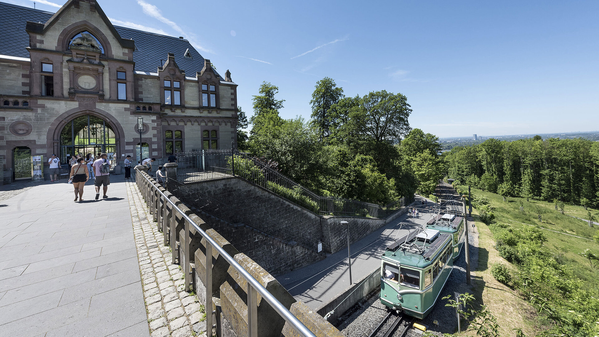 Die Drachenfelsbahn am historischen Bahnhof mit Besuchern, die sich auf den Aufstieg vorbereiten.
