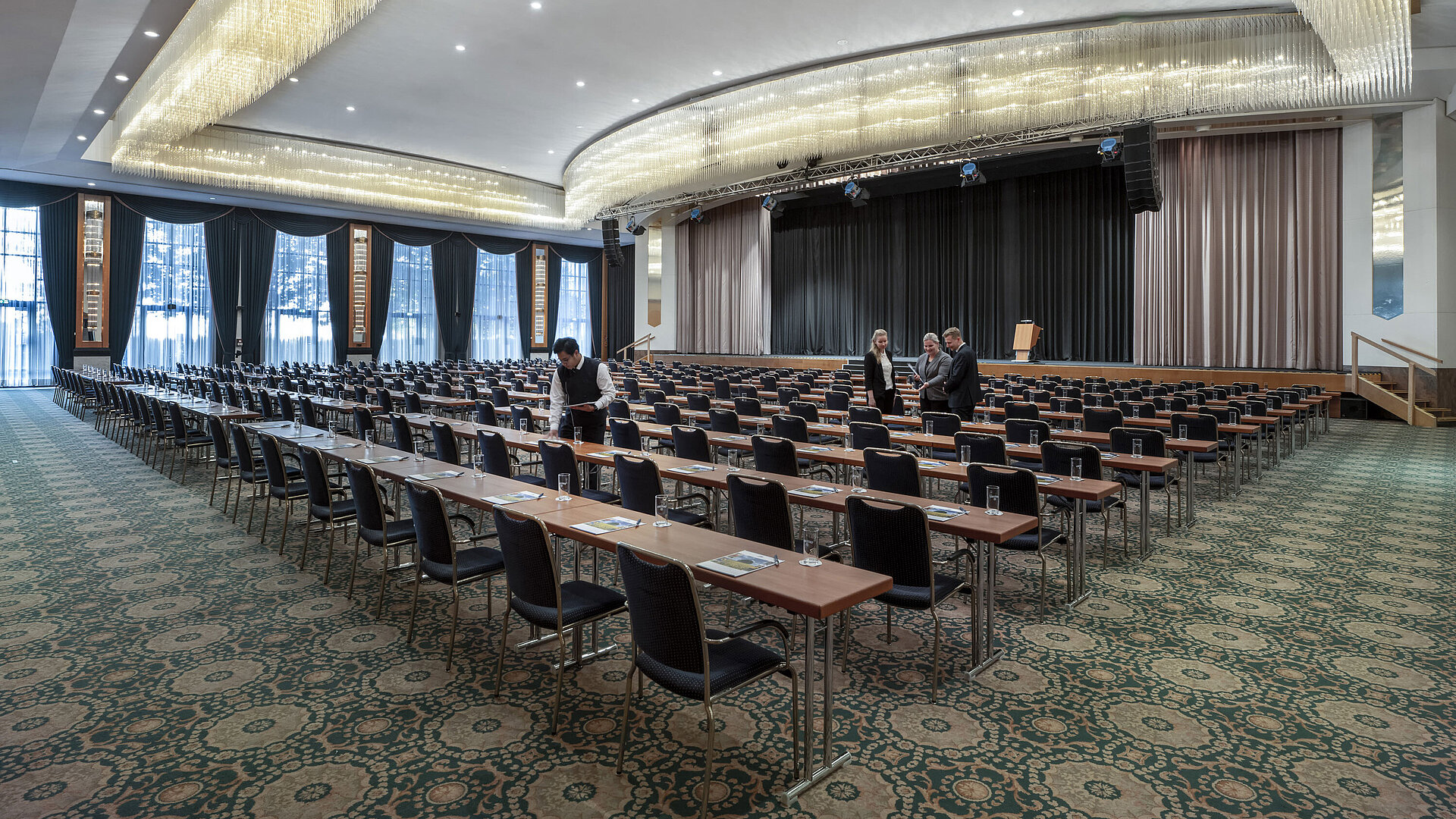Prächtiger Saal im Maritim Hotel Magdeburg mit Bühne, Reihenbestuhlung und luxuriösem Kronleuchter.