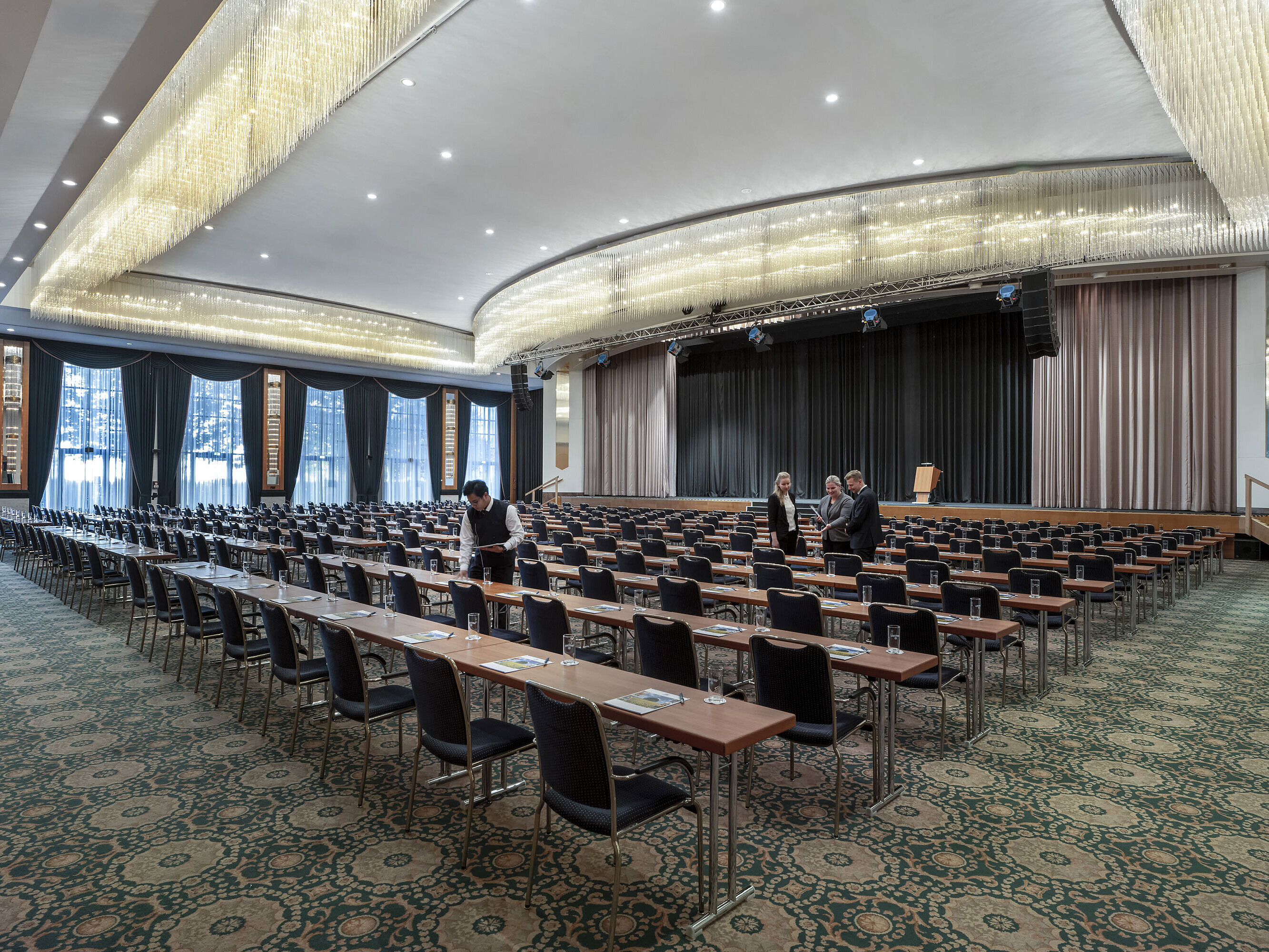 Prächtiger Saal im Maritim Hotel Magdeburg mit Bühne, Reihenbestuhlung und luxuriösem Kronleuchter.