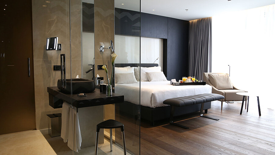 Helles Zimmer mit Doppelbett, Designbad mit Glaswand und Sitzbereich im Maritim Hotel Plaza Tirana