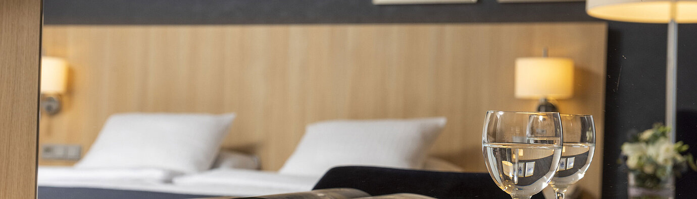 Gemütliches Comfort Zimmer im Maritim Hotel Würzburg mit Spiegel, offenem Bildband und Wassergläsern
