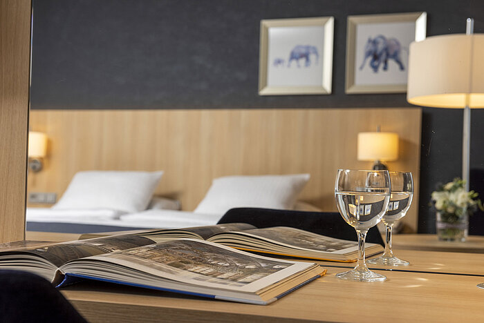 Gemütliches Comfort Zimmer im Maritim Hotel Würzburg mit Spiegel, offenem Bildband und Wassergläsern