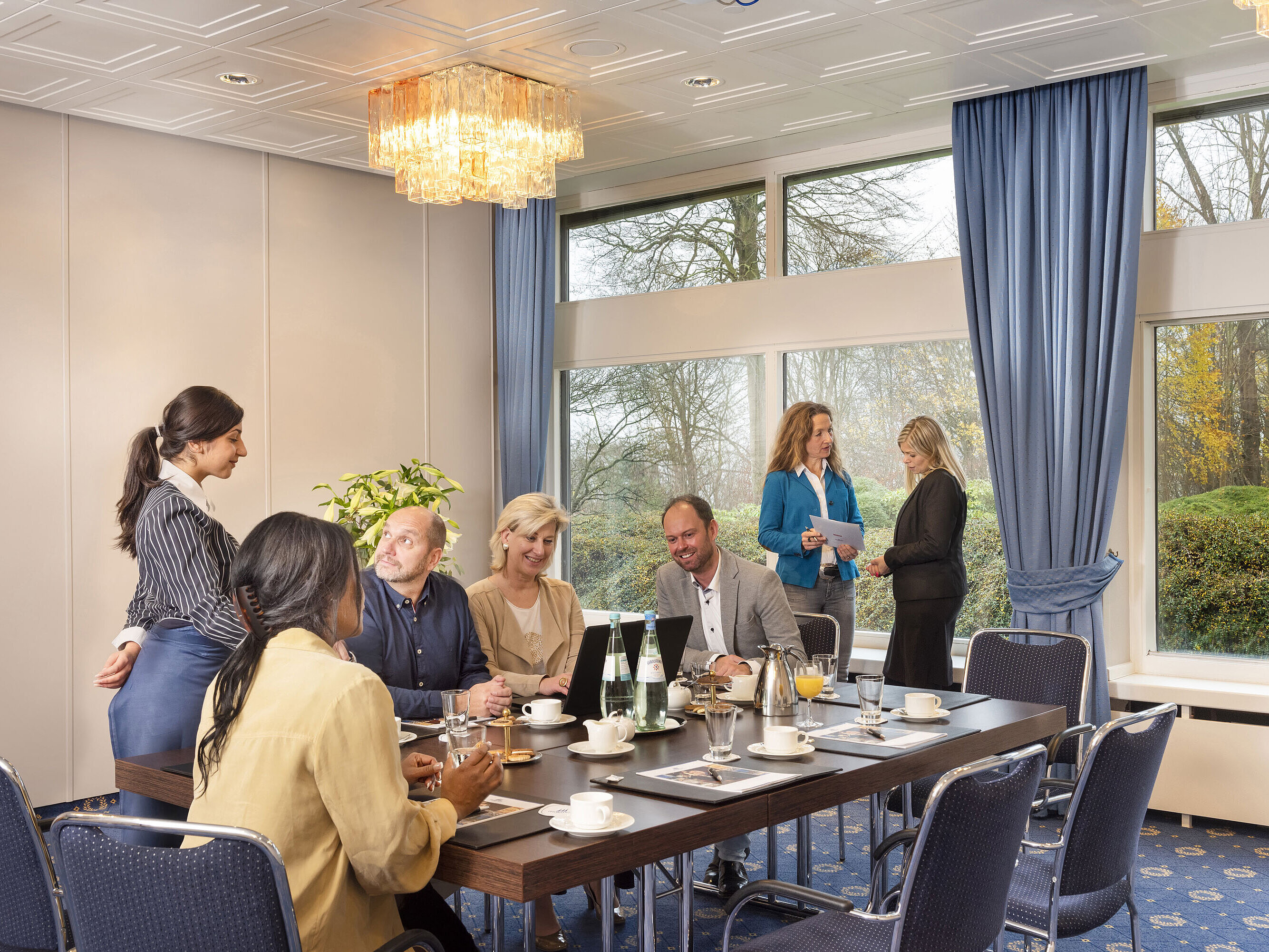 Salon Flensburg im Maritim Hotel Kiel, eine Gruppe von Menschen bei einer Besprechung, freundlicher Service und große Fenster.