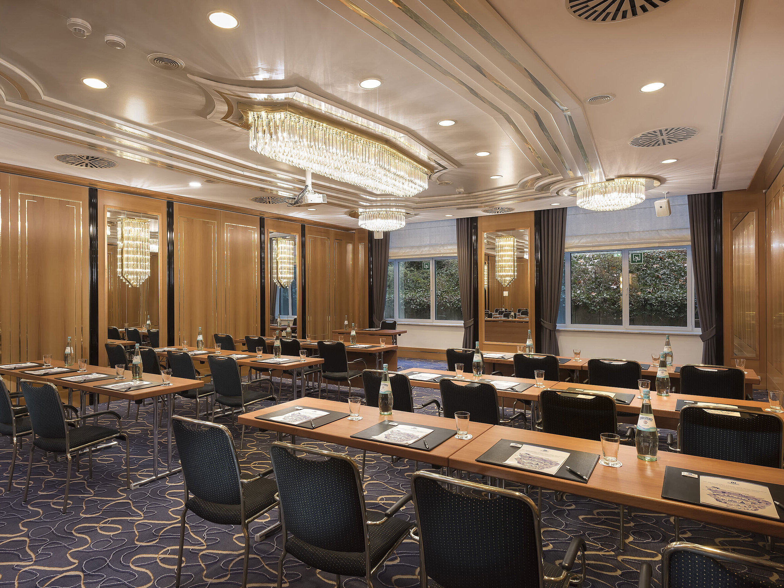 Reihenbestuhlter Tagungsraum mit Tageslicht, Kronleuchtern und Schreibutensilien im Maritim Hotel Stuttgart