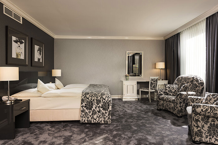 Geräumige Suite im Maritim Hotel Ulm mit edlem Teppich, eleganter Sitzecke und Schminktisch