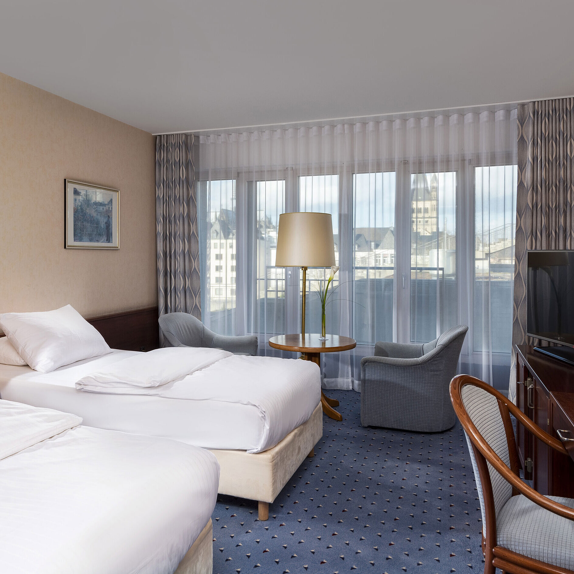 Standard Standard-Twin Zimmer im Maritim Hotel Köln mit zwei Betten, Sitzbereich, Schreibtisch, Flachbildfernseher und großen Fenstern
