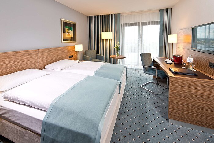 Superior Zimmer im Maritim Hotel Darmstadt mit Doppelbett, Schreibtisch, Sitzecke und Blick auf den Balkon.