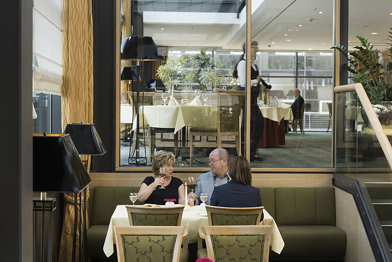 Gäste genießen ein Glas Wein in gemütlicher Atmosphäre im Restaurant des Maritim Hotel Dresden.
