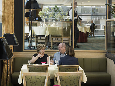 Gäste genießen ein Glas Wein in gemütlicher Atmosphäre im Restaurant des Maritim Hotel Dresden.