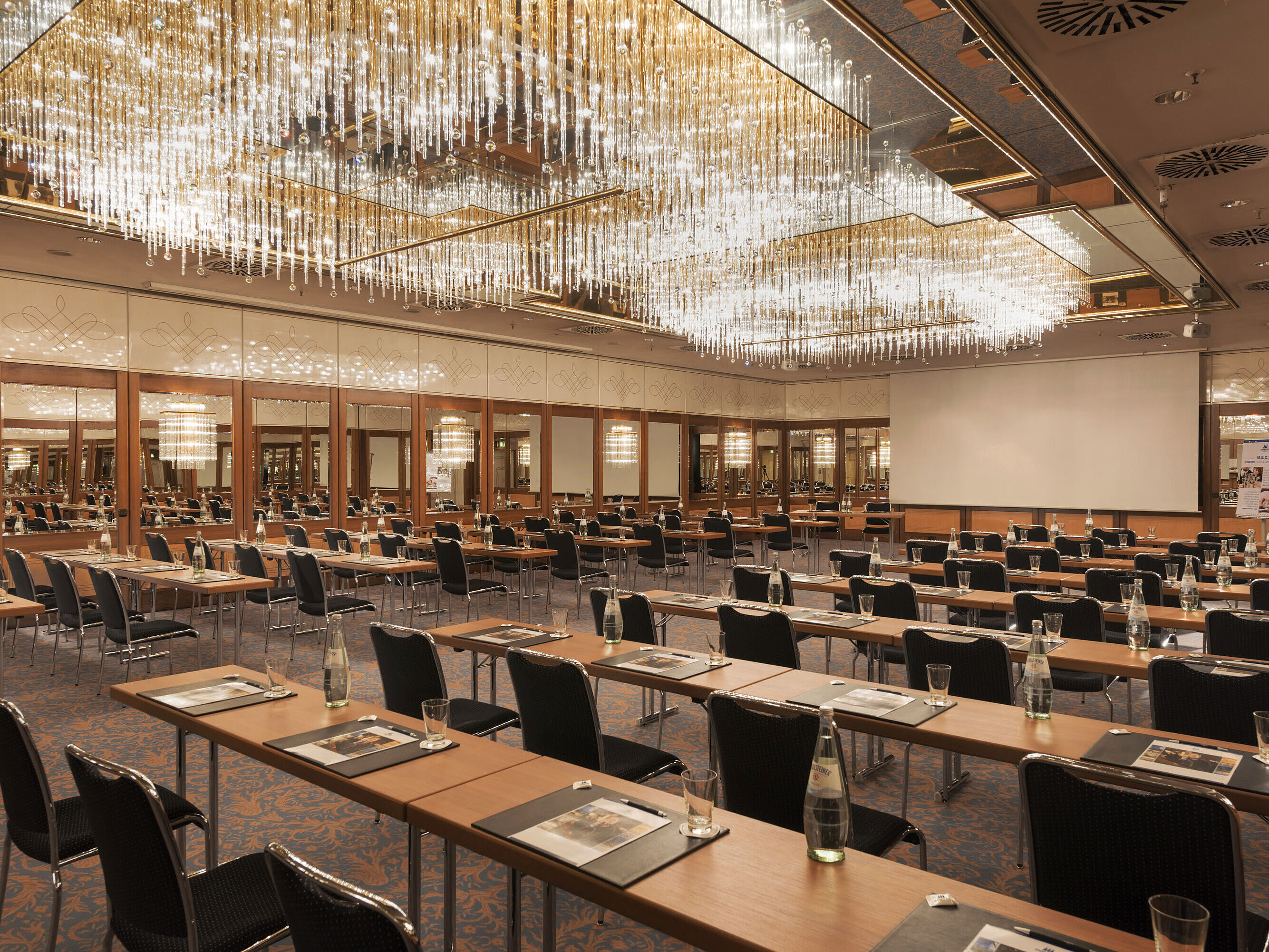 Großzügiger Konferenzsaal mit Kristallleuchtern und gespannter Atmosphäre im Maritim Hotel München