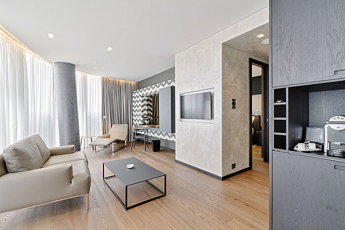 Lounge mit Sofa, TV, Designspiegel und Relaxliege im Maritim Hotel Plaza Tirana mit Tageslicht