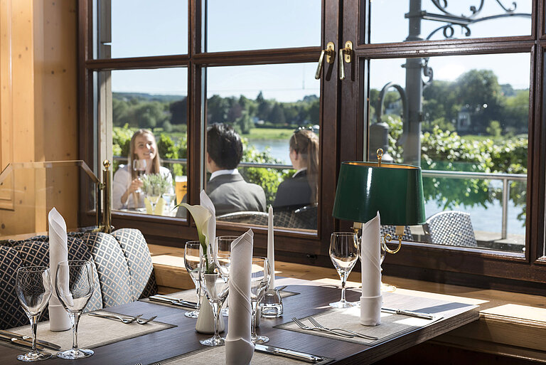 Stilvoll gedeckter Tisch im Restaurant des Maritim Hotel Königswinter mit Blick auf den Rhein und die Natur.