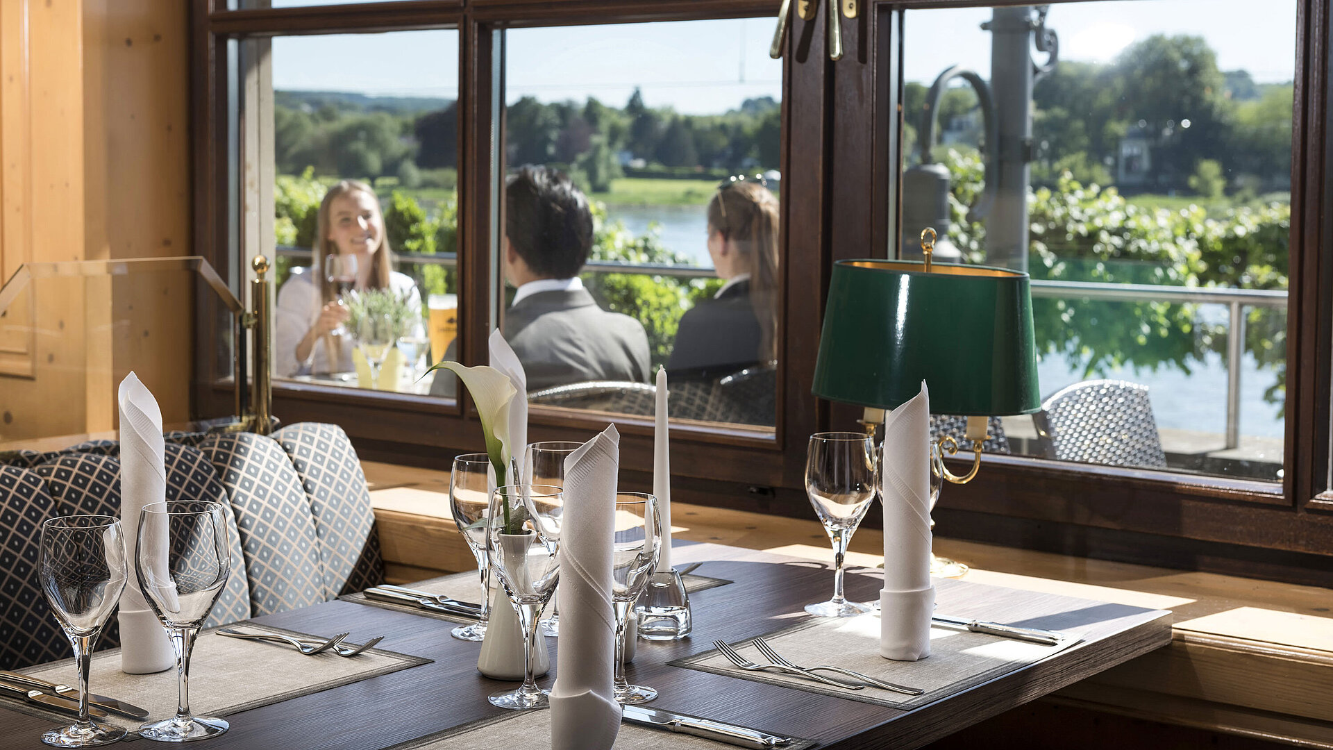 Stilvoll gedeckter Tisch im Restaurant des Maritim Hotel Königswinter mit Blick auf den Rhein und die Natur.
