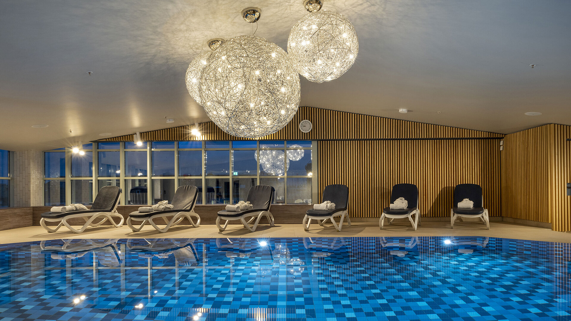Schwimmbad mit blauen Fliesen und Liegen im Maritim Hotel München