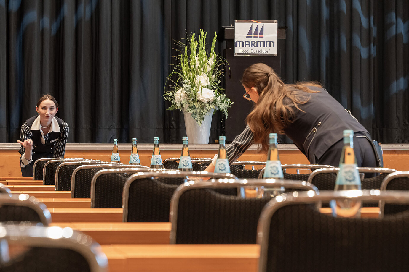 Mitarbeiter bereiten Tagungsraum mit Bühne im Maritim Hotel Düsseldorf vor.