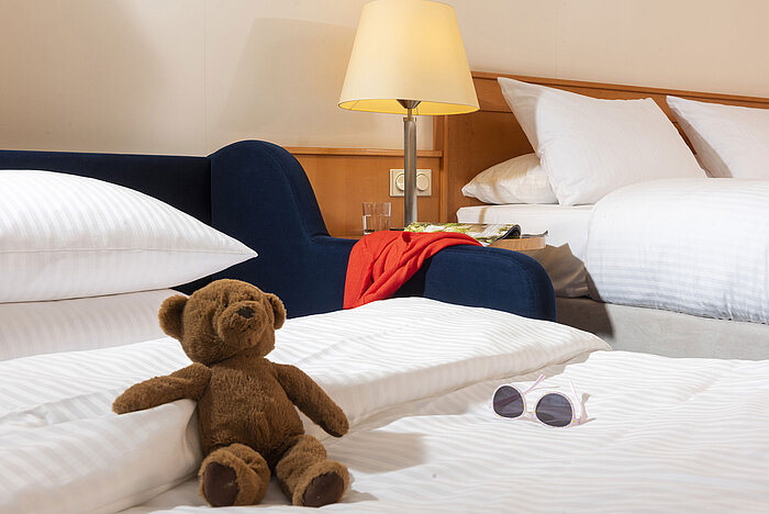 Gemütliches Familienzimmer im Maritim Hotel Frankfurt mit Kuscheltier, Sonnenbrille und weichen Betten.