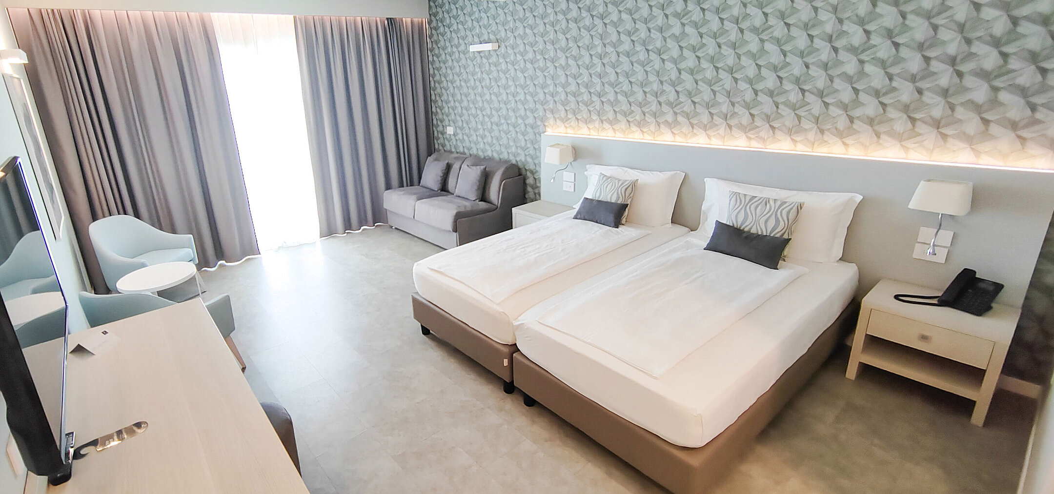 Großzügiges Zimmer im Maritim Resort Calabria mit Twin-Bett, Sofa, Schreibtisch und hellen Farben
