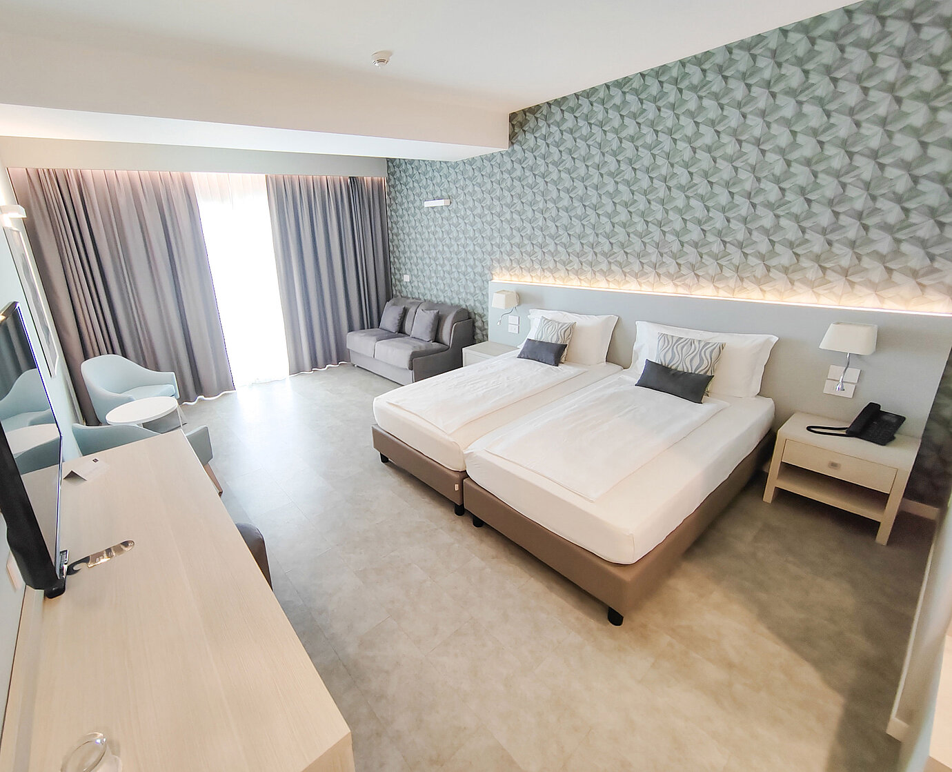 Großzügiges Zimmer im Maritim Resort Calabria mit Twin-Bett, Sofa, Schreibtisch und hellen Farben