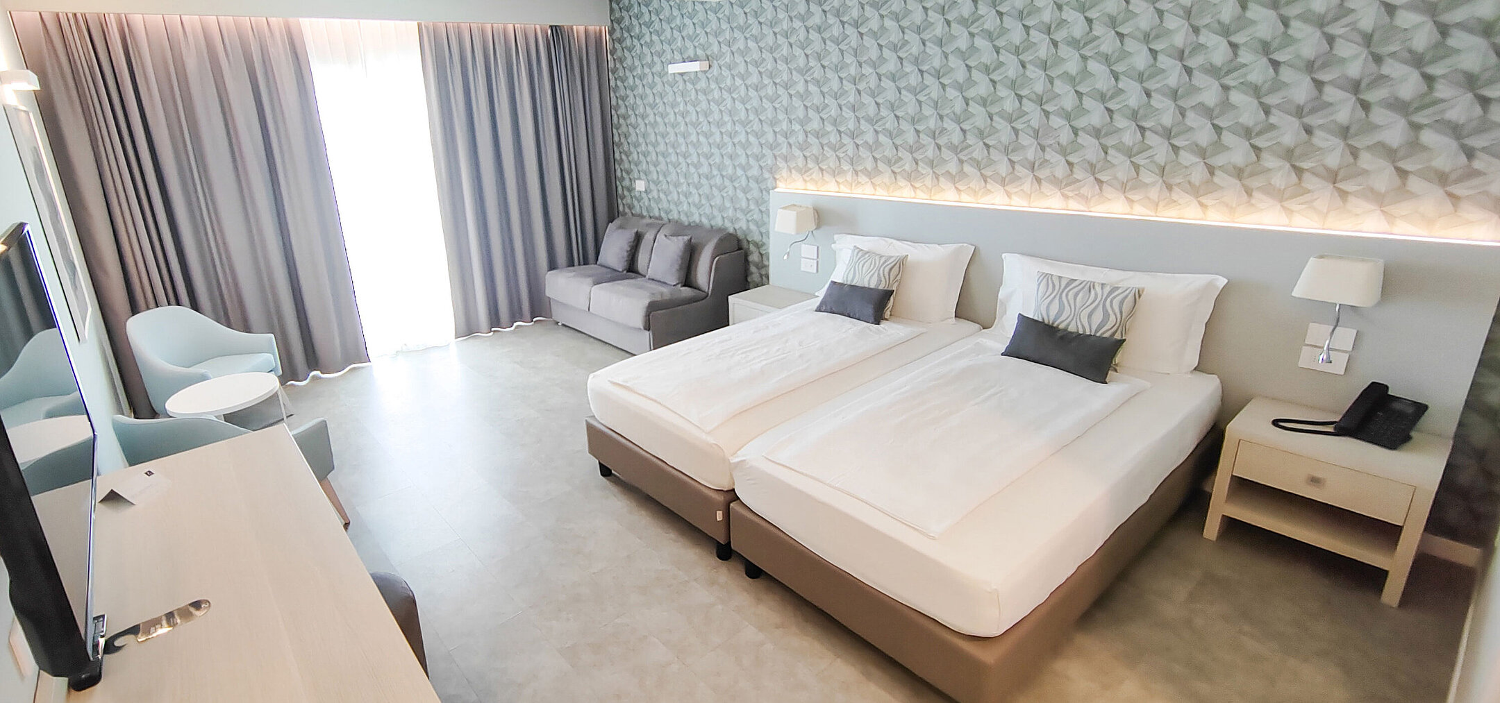 Großzügiges Zimmer im Maritim Resort Calabria mit Twin-Bett, Sofa, Schreibtisch und hellen Farben